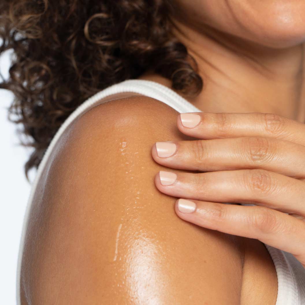 Female model rubbing the body oil on her arm.