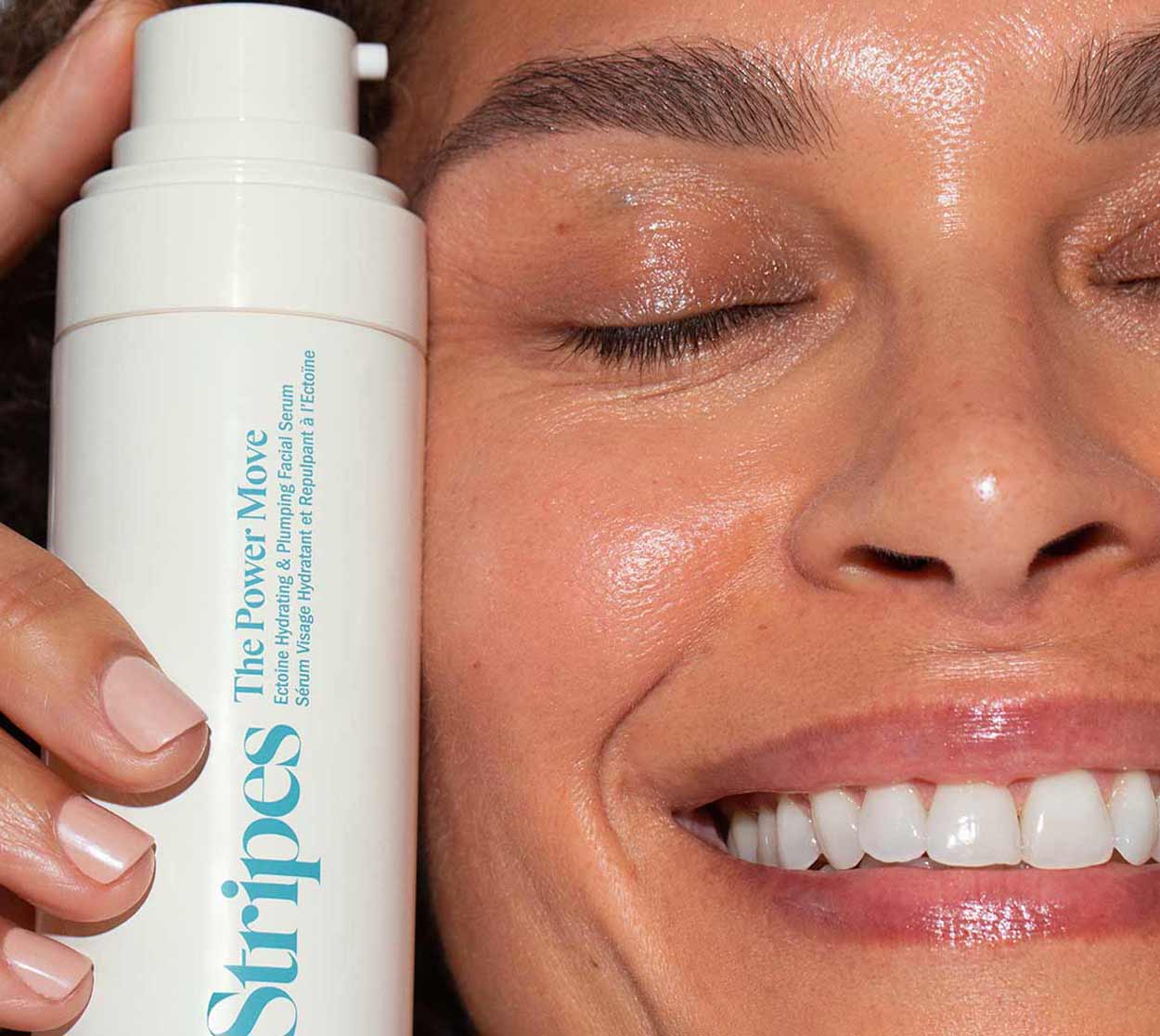 Close up of woman holding The Power Move Facial serum next to her face